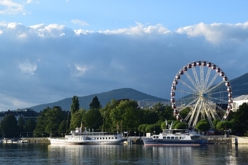 A Ferris wheel and two boats in Lake Geneva.